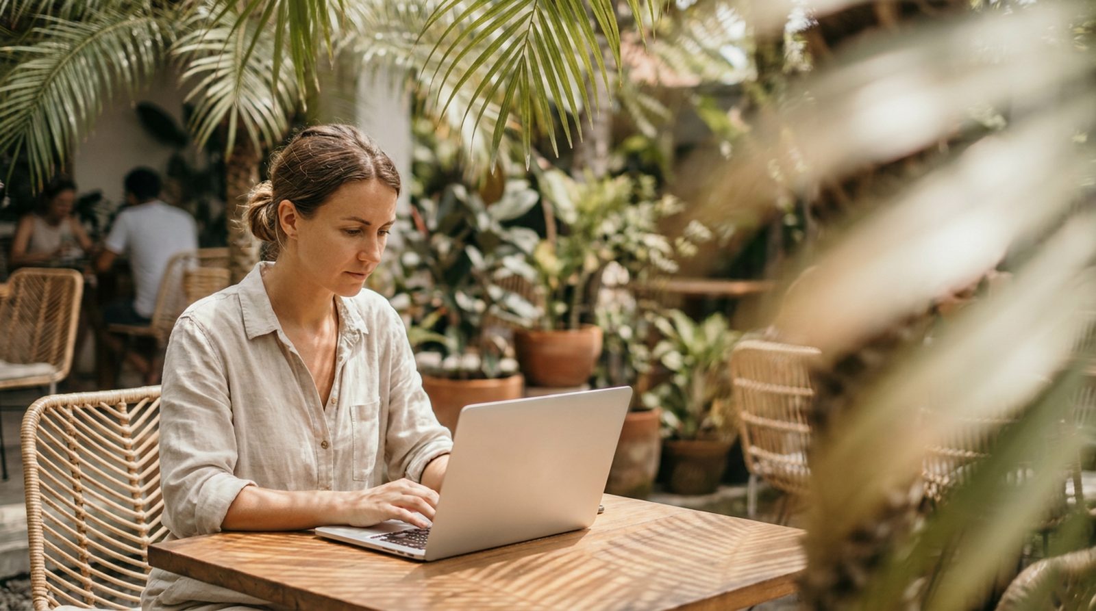 A woman working on a laptop at an outdoor cafe in tropical Asia